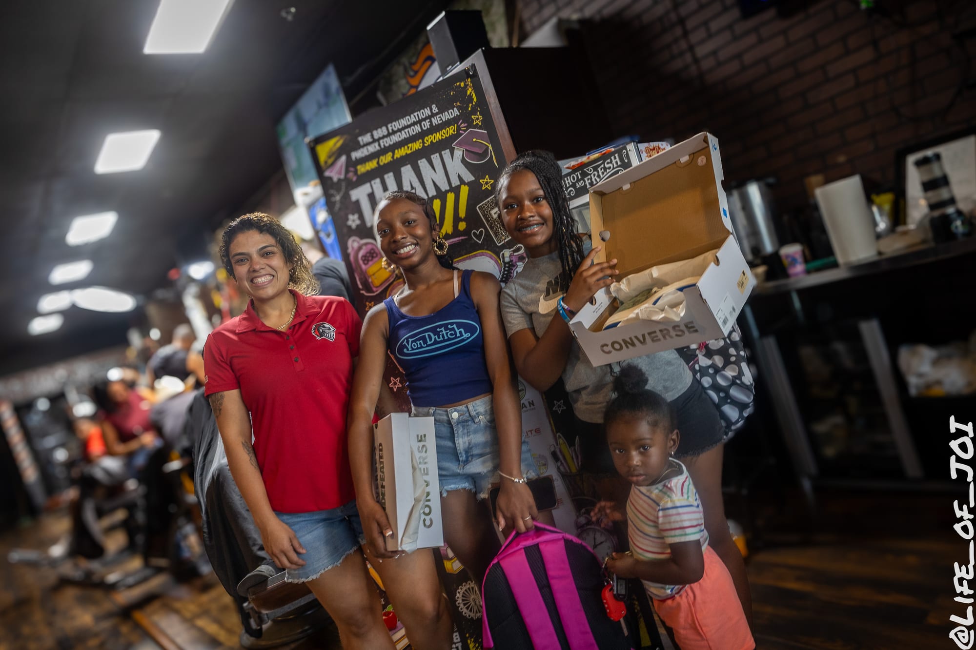 Families line the shop holding Converse boxes and new backpacks at the back to school giveaway.