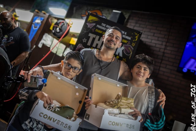 A father and two children hold their new Converse boxes at the thank you banner.