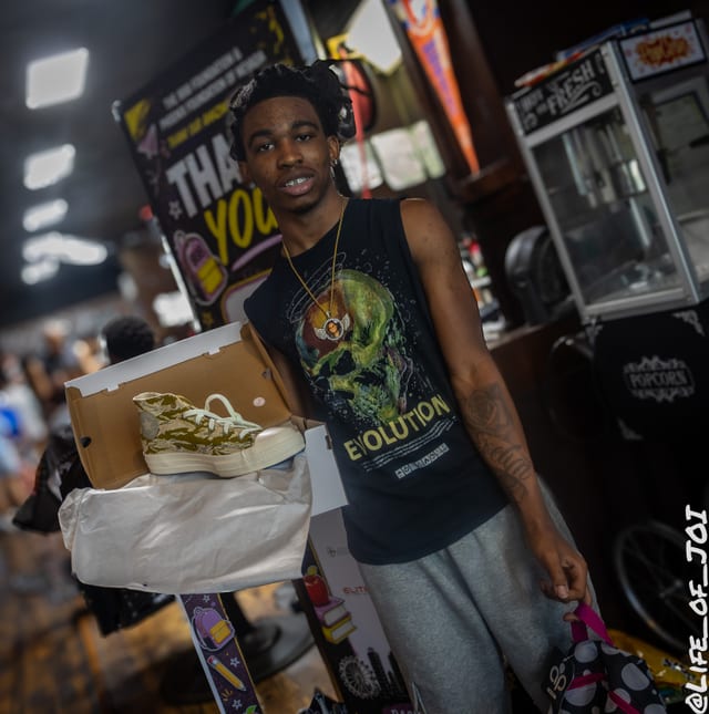 A teenager lifts his new Converse sneakers out of the box at the event.