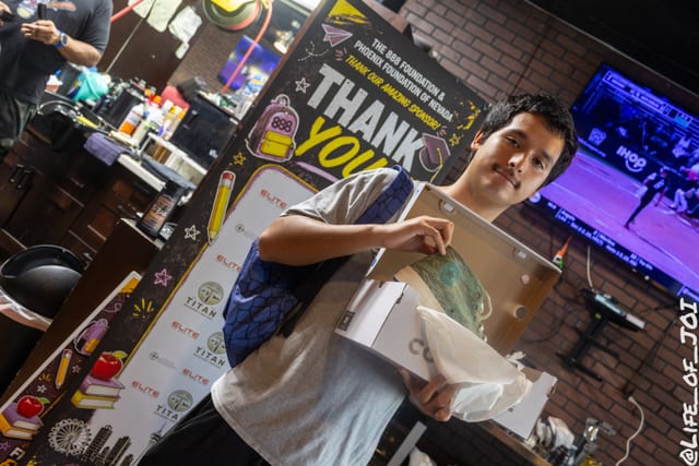 A student holds a box of sneakers and a bag of school supplies at the 888 Fresh Start Experience.