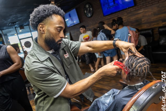 A stylist works carefully on a young client’s braids during the free grooming event.